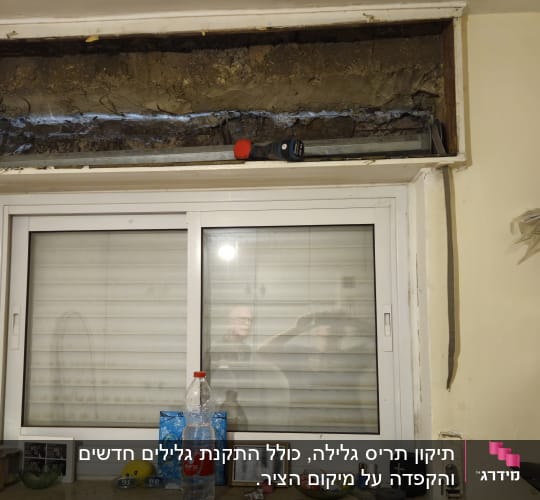 חלון עם תריסים ומדף עם חפצים שונים